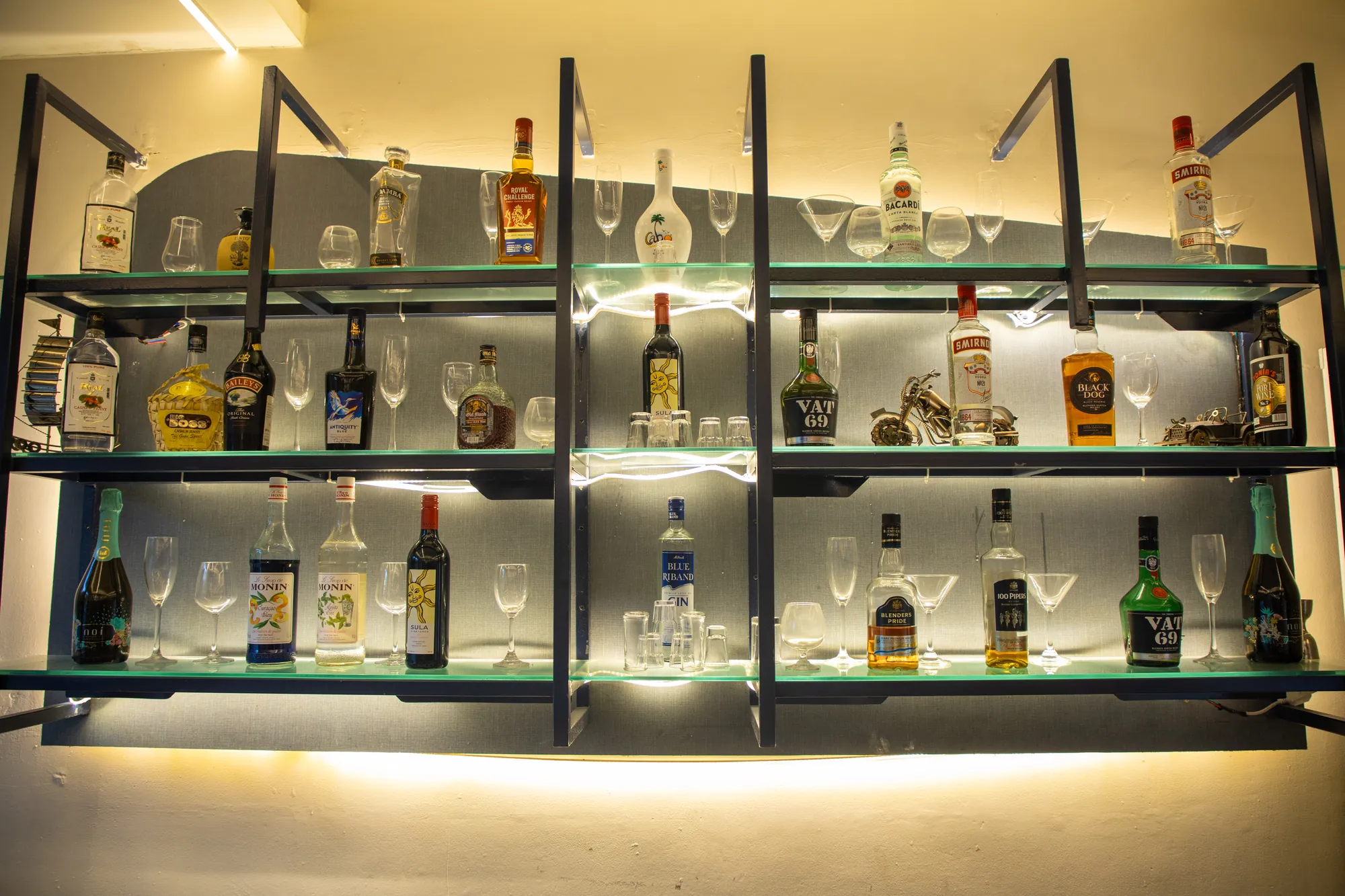 Backlit glass shelves stocked with whisky, gin, rum and vodka