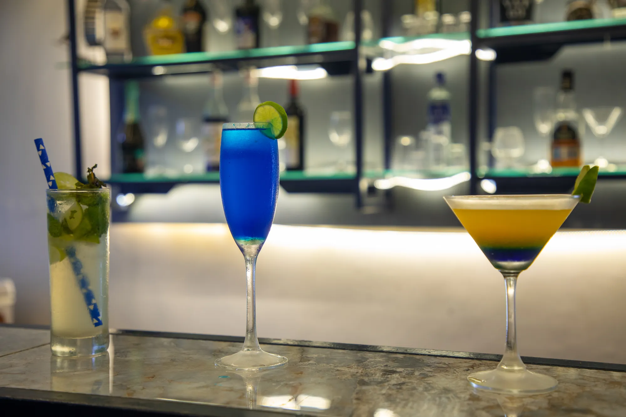 Cocktails lined up on the bar top in front of the shelves