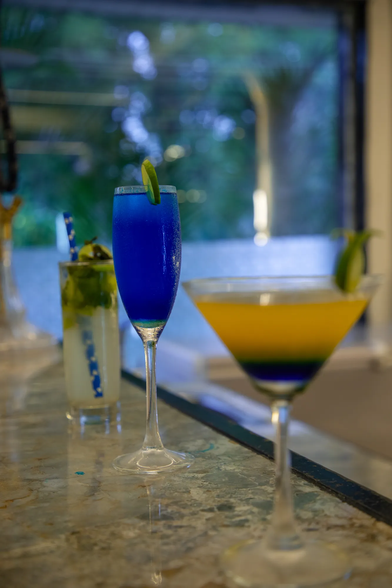 Blue cocktail, mojito and layered martini on the marble bar top