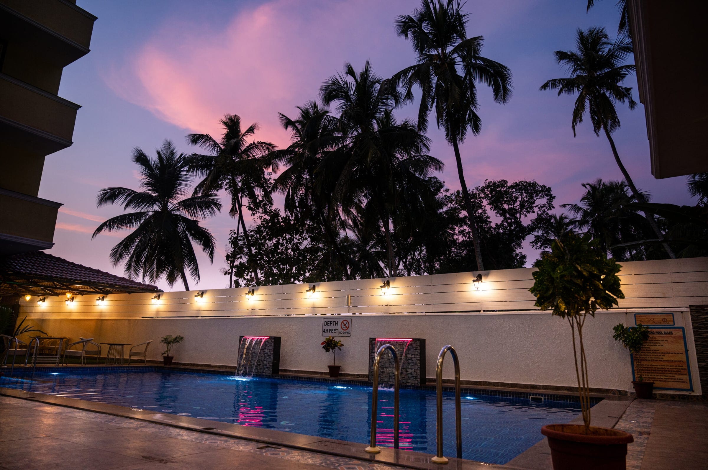 Swimming pool at sunset with palm trees and lanterns
