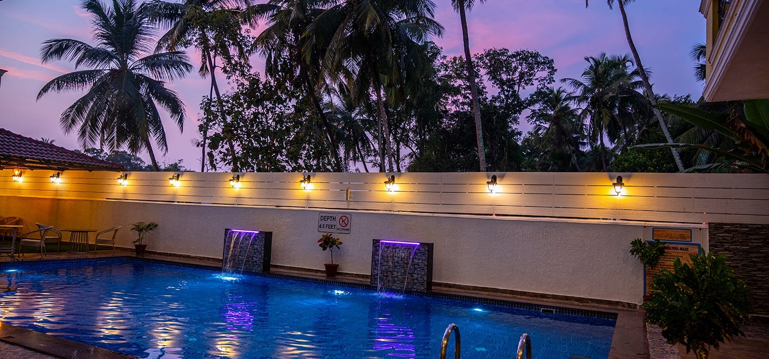 Swimming pool at dusk with lanterns and coconut palms